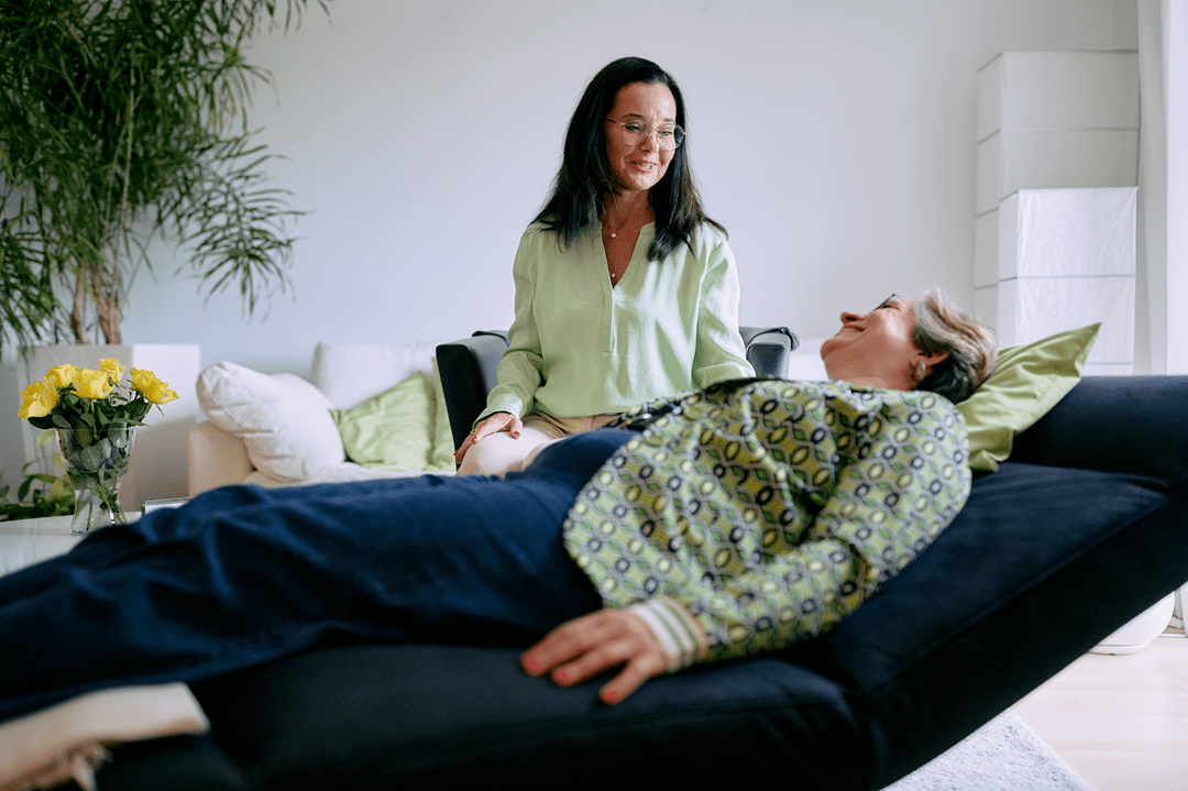 Therapeutin mit lächelnder Patientin auf Liege.